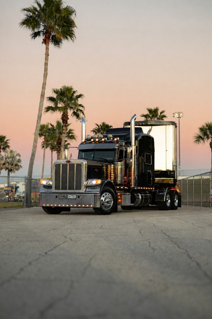 Black Peterbilt semi-truck with chrome trailer at sunset